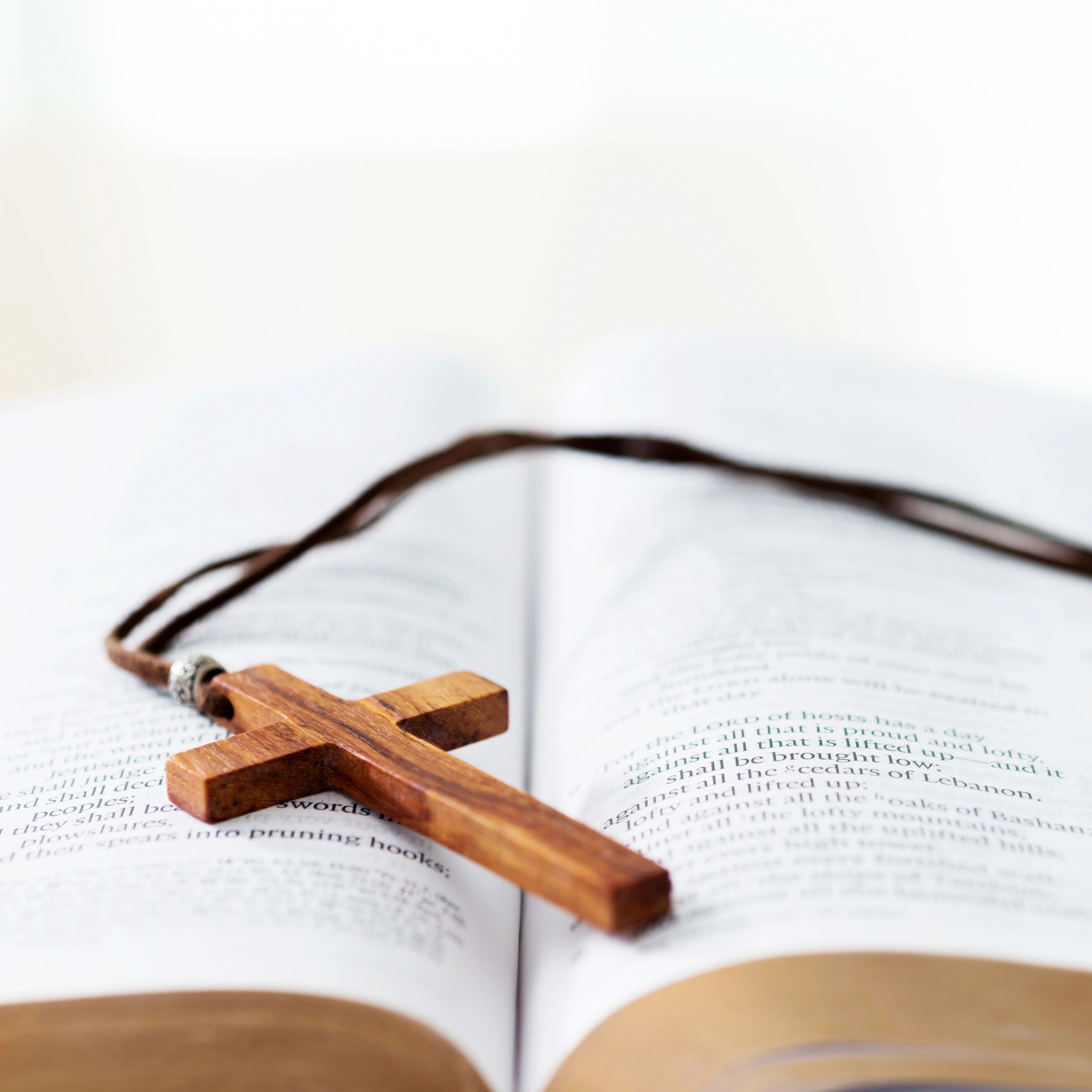 Bible and cross resting on a desk in soft light